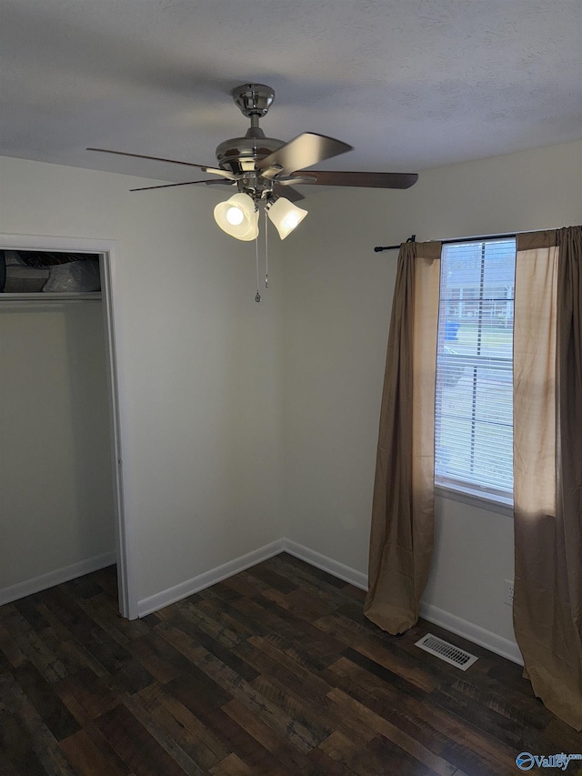 unfurnished bedroom featuring baseboards, visible vents, dark wood finished floors, and a ceiling fan