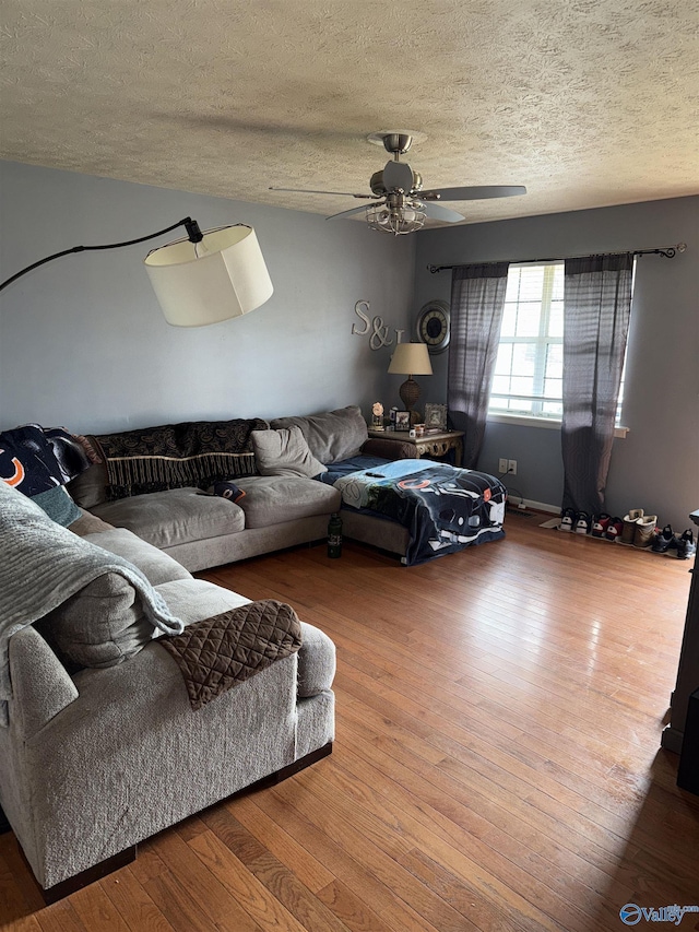 living room with wood-type flooring, a textured ceiling, and a ceiling fan