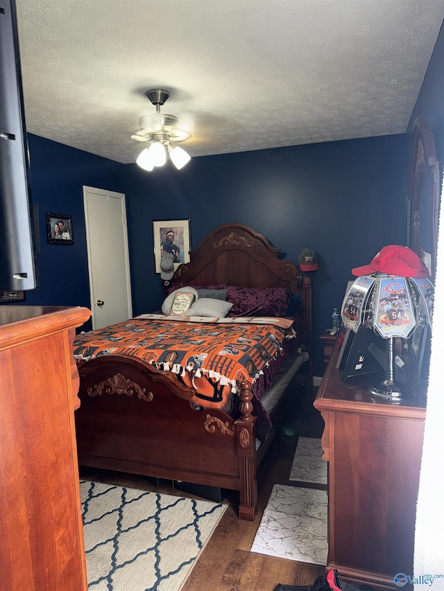 bedroom with dark wood-type flooring, a textured ceiling, and a ceiling fan