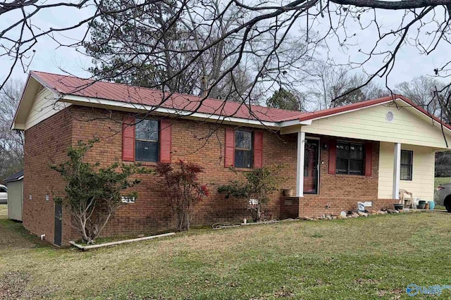 single story home featuring metal roof, brick siding, and a front yard