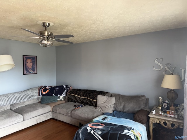 living area featuring dark wood-style floors, ceiling fan, and a textured ceiling