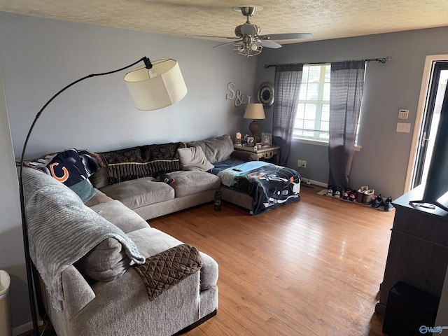 living area with a textured ceiling, ceiling fan, and light wood finished floors