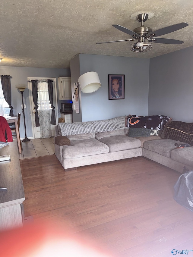 living area featuring a textured ceiling, wood finished floors, and a ceiling fan