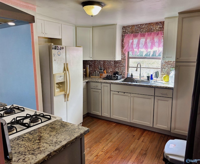 kitchen featuring white refrigerator with ice dispenser, decorative backsplash, light hardwood / wood-style floors, and gray cabinets