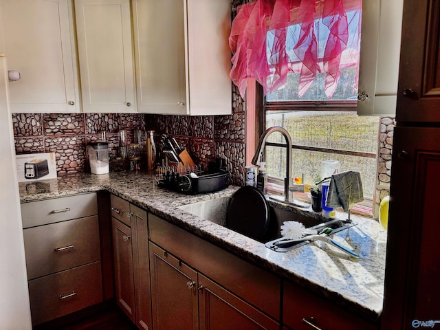 kitchen with backsplash, light stone counters, and sink