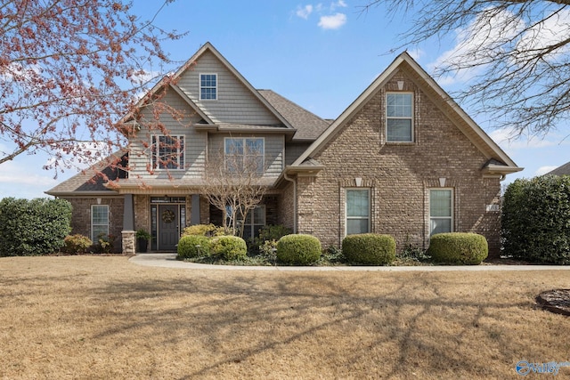 craftsman inspired home featuring brick siding, a front lawn, and a shingled roof