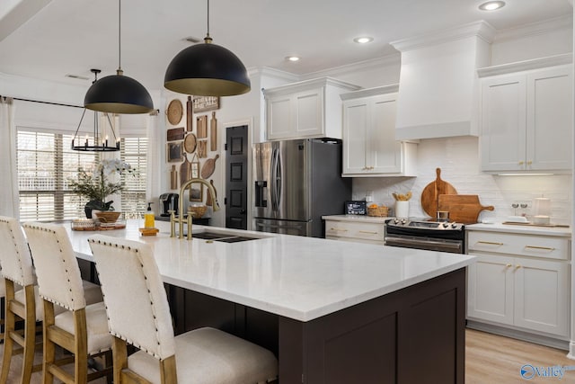 kitchen featuring crown molding, premium range hood, appliances with stainless steel finishes, white cabinetry, and a sink