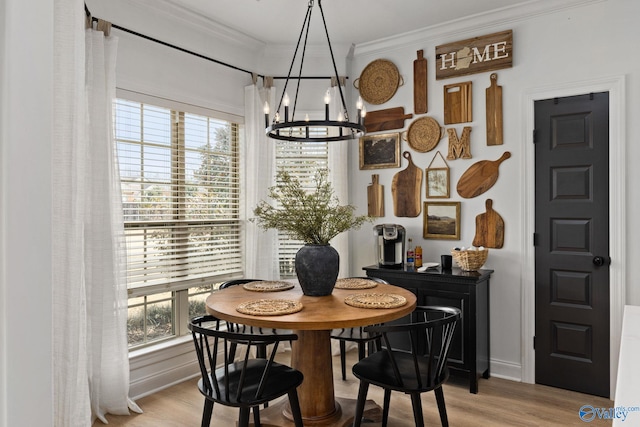 dining room featuring baseboards, wood finished floors, a notable chandelier, and ornamental molding