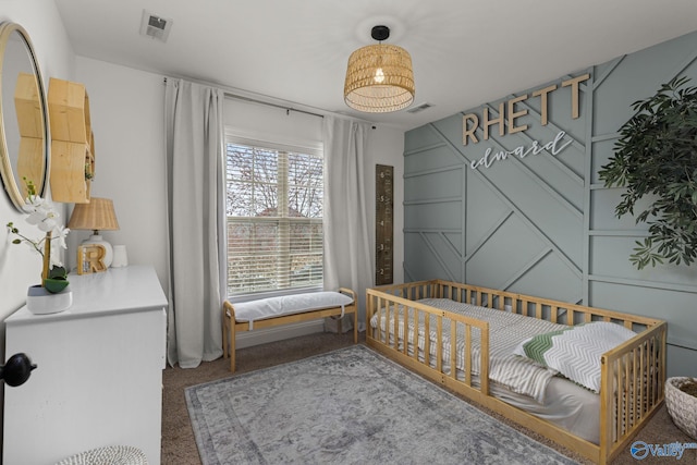 carpeted bedroom featuring visible vents and a decorative wall