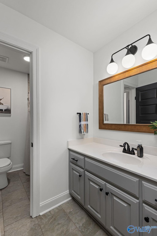 bathroom featuring visible vents, toilet, vanity, and baseboards