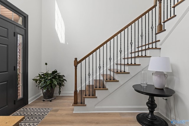 foyer entrance featuring stairway, baseboards, and wood finished floors