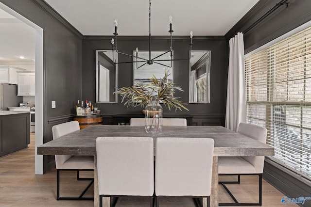 dining room featuring light wood finished floors, crown molding, and an inviting chandelier