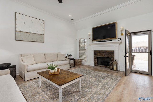 living room featuring a fireplace, crown molding, baseboards, and wood finished floors