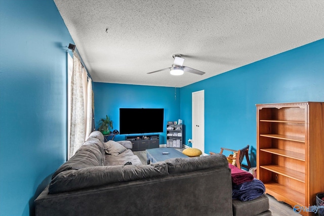 living room with a textured ceiling, wood finished floors, and a ceiling fan