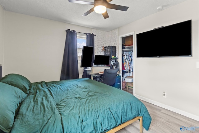 bedroom featuring a textured ceiling, wood finished floors, a ceiling fan, baseboards, and a closet