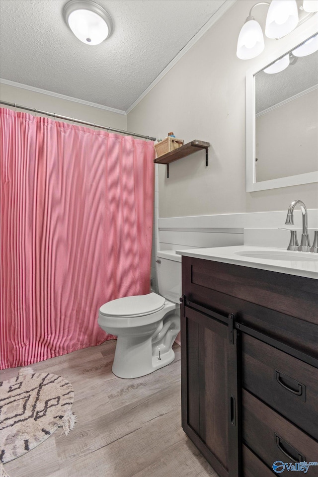 bathroom featuring a textured ceiling, wood finished floors, crown molding, and vanity