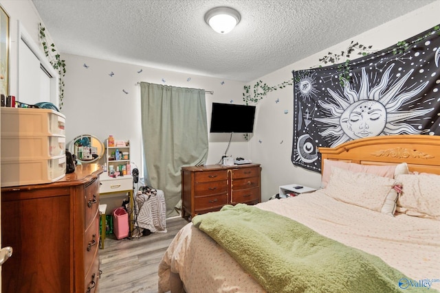 bedroom featuring light wood finished floors and a textured ceiling