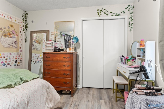 bedroom featuring a closet, light wood-style flooring, and a textured ceiling