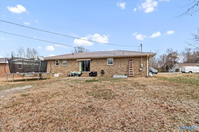 back of house with a patio, brick siding, and a trampoline