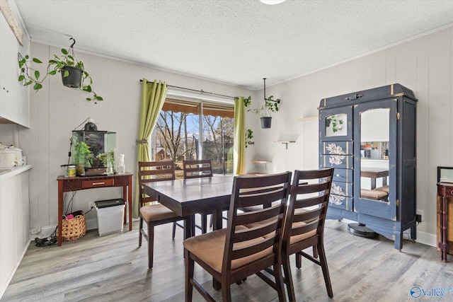 dining area with a textured ceiling, light wood-style flooring, and crown molding