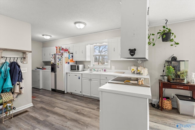 kitchen with washing machine and dryer, a sink, white cabinets, light countertops, and stainless steel microwave