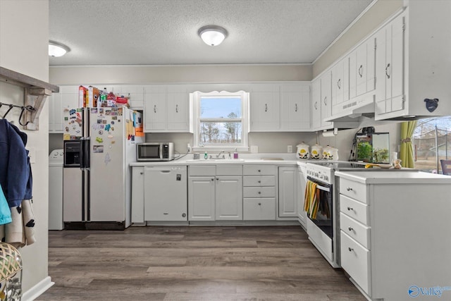 kitchen with white appliances, light countertops, under cabinet range hood, white cabinetry, and a sink