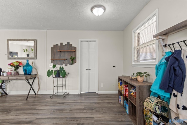 interior space with a textured ceiling, baseboards, and dark wood-type flooring