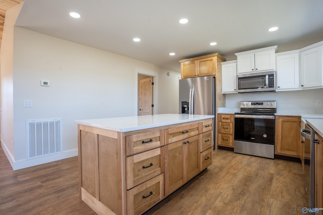 kitchen with wood finished floors, visible vents, appliances with stainless steel finishes, and a center island