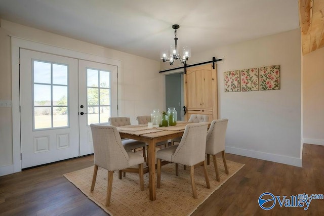 dining room featuring baseboards, dark wood-style flooring, french doors, a barn door, and a notable chandelier