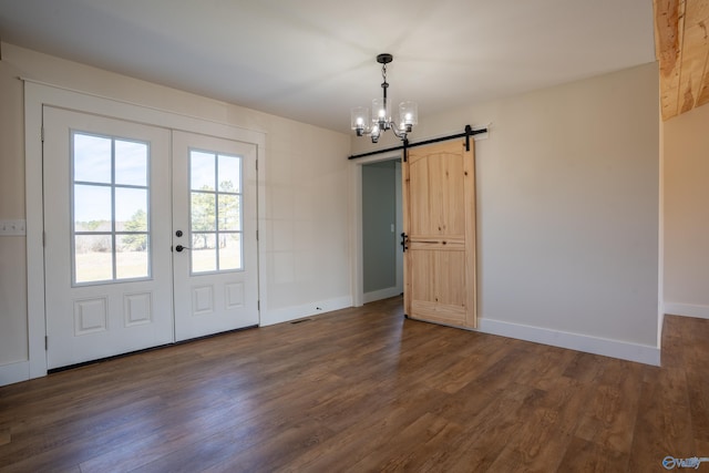 unfurnished dining area featuring a barn door, baseboards, dark wood finished floors, and french doors