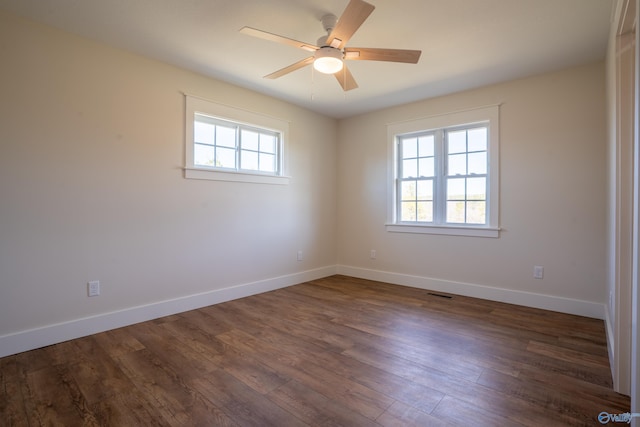 empty room with a wealth of natural light, baseboards, dark wood-style floors, and a ceiling fan