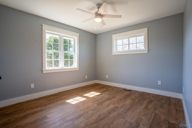 spare room with a ceiling fan, dark wood-type flooring, baseboards, and visible vents