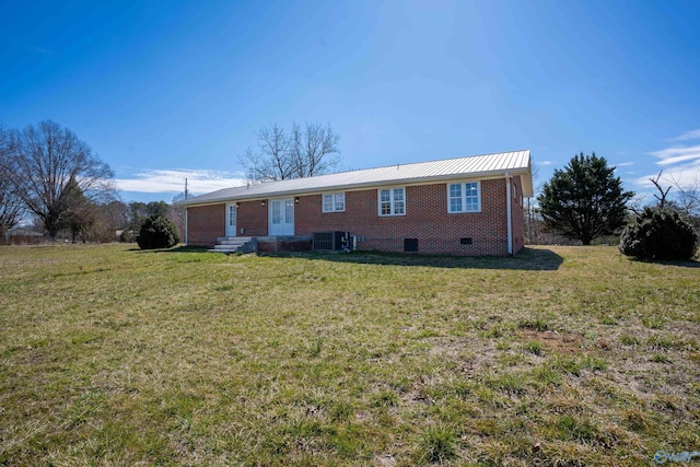 view of front of house featuring a front lawn, central AC, metal roof, crawl space, and brick siding