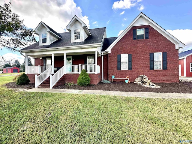 new england style home featuring covered porch, brick siding, and a front lawn