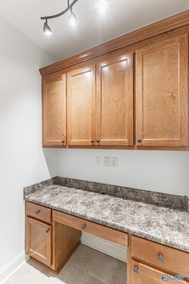 kitchen featuring light tile patterned floors, built in study area, and baseboards