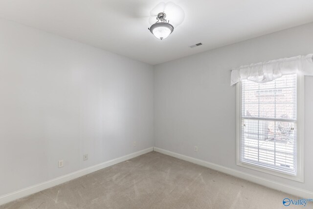 unfurnished room featuring a wealth of natural light, visible vents, light colored carpet, and baseboards