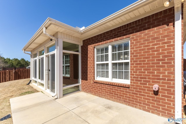 view of patio / terrace featuring fence and a sunroom