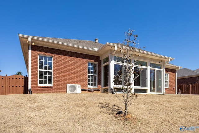 rear view of house featuring ac unit, fence, brick siding, and a sunroom