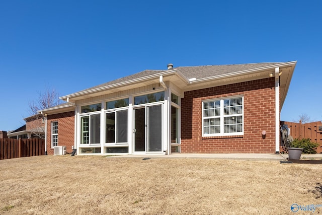 back of house with fence, a sunroom, a shingled roof, central air condition unit, and brick siding