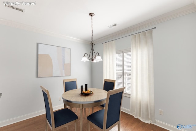 dining space featuring an inviting chandelier, crown molding, wood finished floors, and visible vents