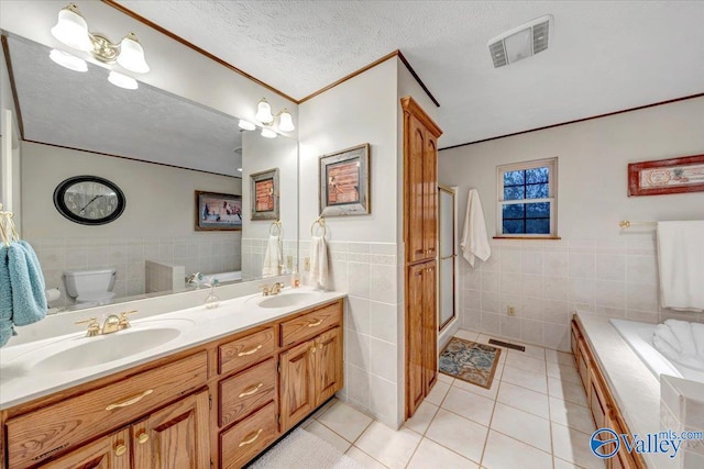 bathroom featuring toilet, tile patterned flooring, vanity, tile walls, and a textured ceiling