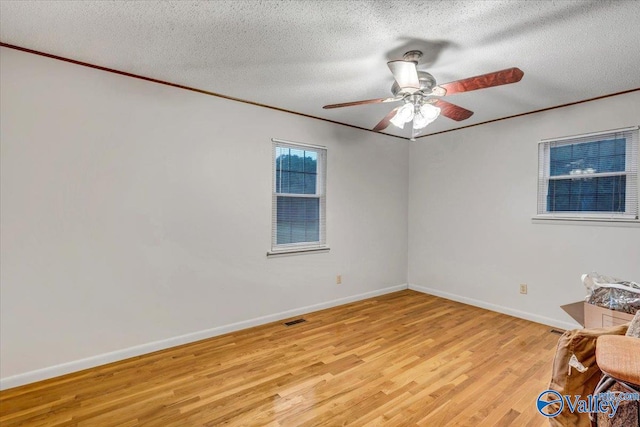 spare room with ceiling fan, crown molding, a textured ceiling, and light hardwood / wood-style flooring