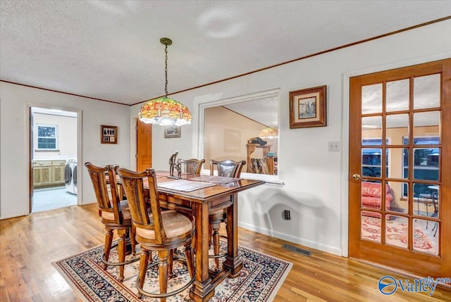 dining area featuring independent washer and dryer, a textured ceiling, and light hardwood / wood-style floors