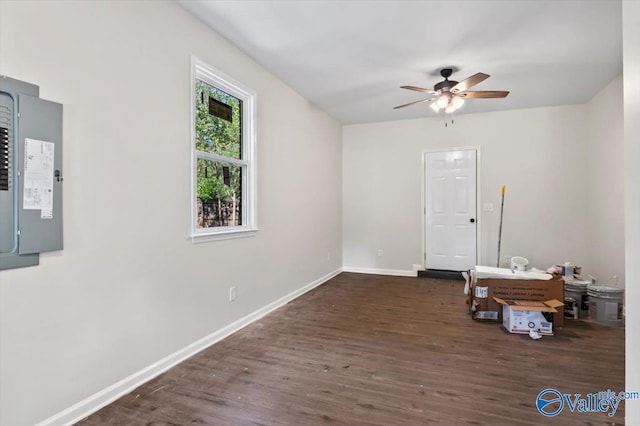 spare room with dark hardwood / wood-style flooring, electric panel, and ceiling fan