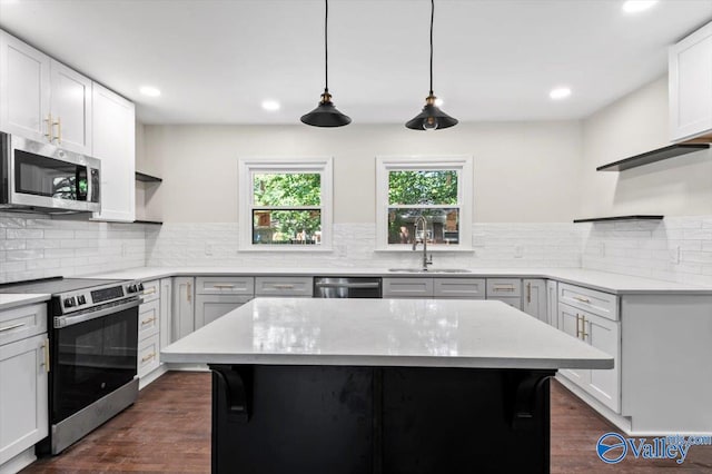 kitchen featuring pendant lighting, a kitchen island, sink, and stainless steel appliances