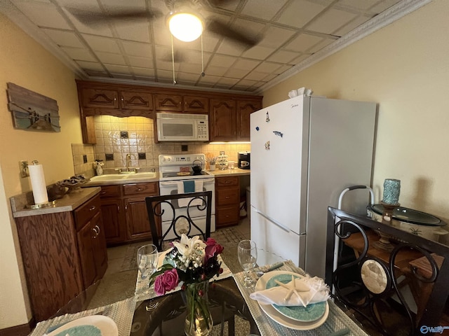 kitchen featuring tasteful backsplash, sink, white appliances, and crown molding