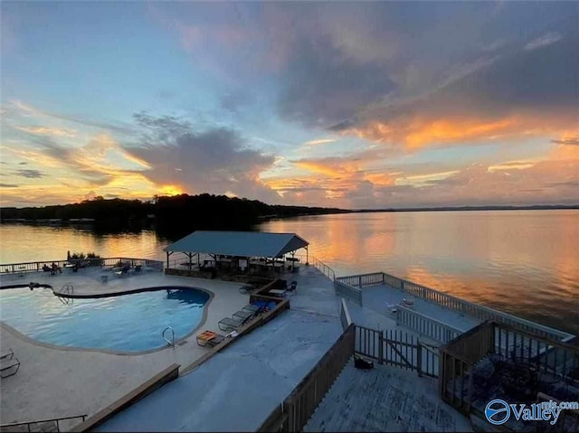 pool at dusk with a patio and a water view