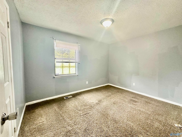 carpeted empty room with a textured ceiling