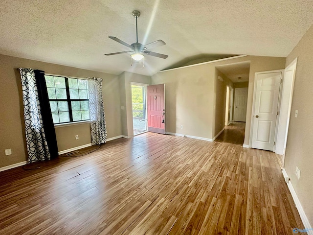 empty room with a textured ceiling, vaulted ceiling, ceiling fan, and hardwood / wood-style flooring