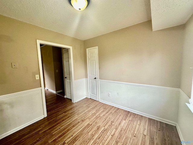 unfurnished room with a textured ceiling and wood-type flooring